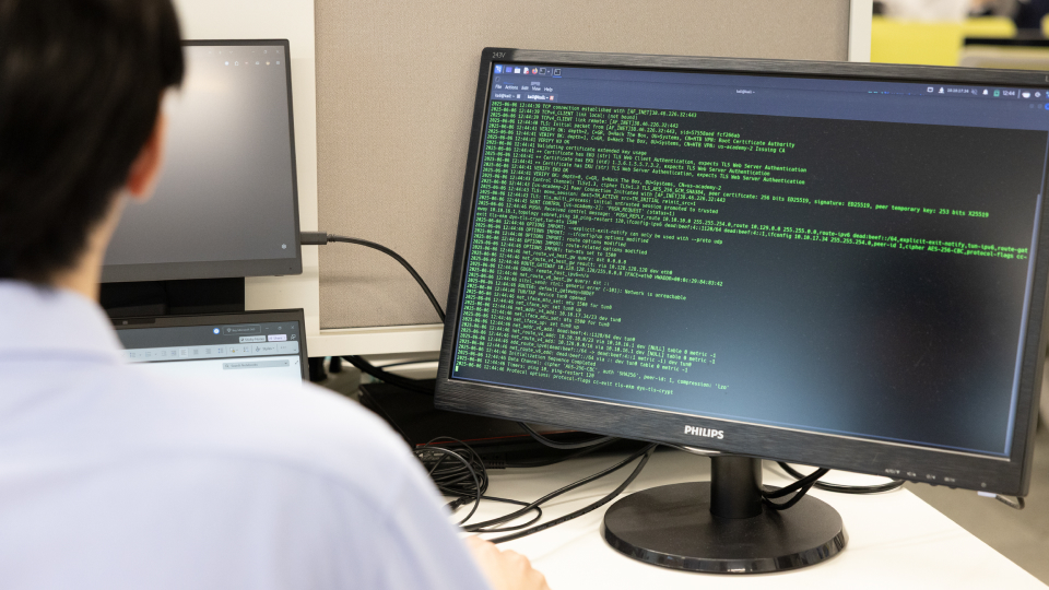 従業員がPCを使用している様子。右側にあるモニターにはコードが表示されている。